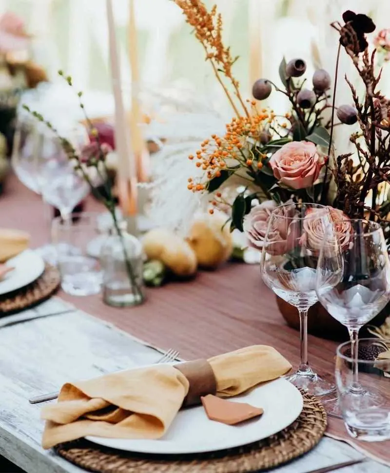 Festlich gedeckter Tisch für zwei Personen mit Herbstblumen, Kerzen und Weingläsern