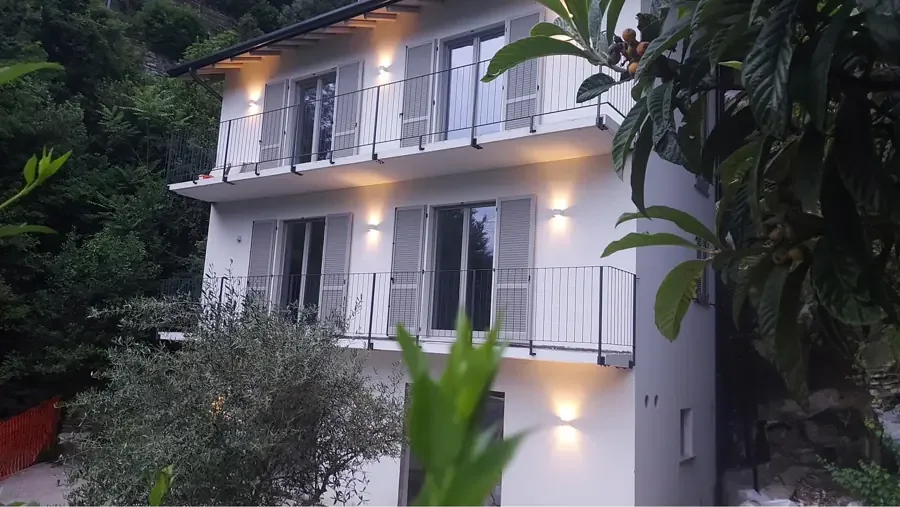 Beleuchtete Villa Avatelli mit Balkonen zwischen Bäumen am Hang über dem Comer See
